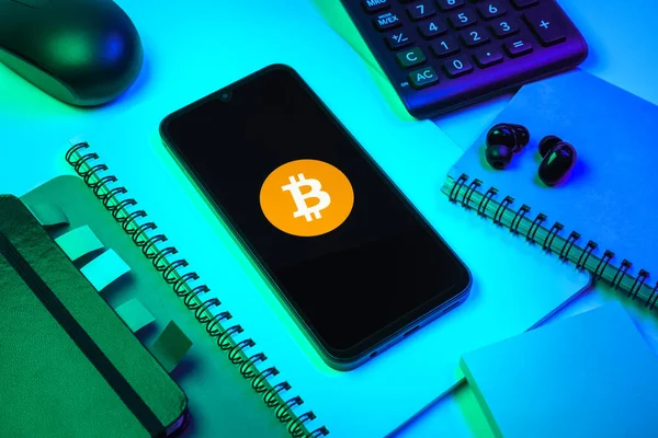 Prag, Çek Cumhuriyeti - 08 18 2025: Merkezde Bitcoin logosu sergilenen bir cep telefonu ile ofis malzemeleri düzenlemesi. Bitcoin merkezi olmayan işlemler için dijital bir kripto para birimidir.