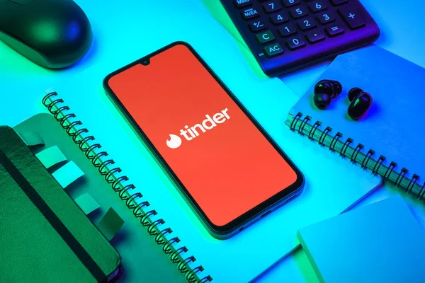 Prag, Çek Cumhuriyeti - 08 18 2025: Merkezde Tinder logosu sergilenen bir cep telefonu ile ofis malzemeleri düzenlemesi. Tinder insanları eşleştirmek ve bağlamak için bir randevu uygulaması.