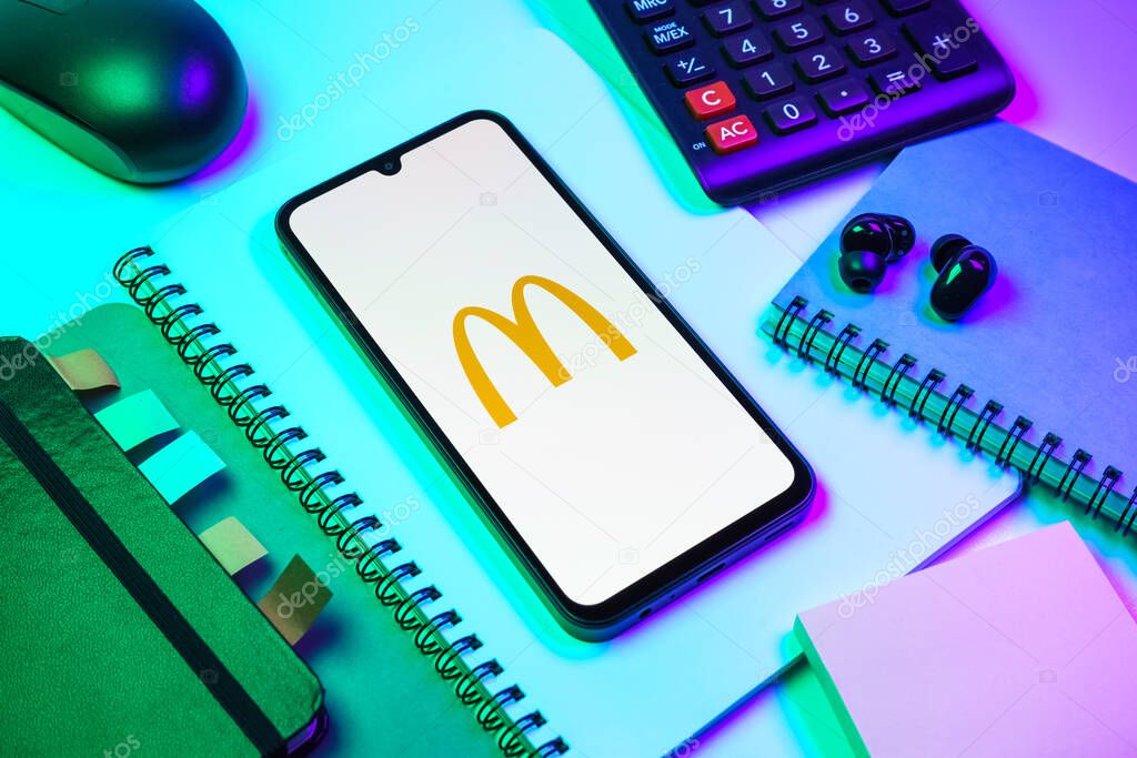 Prague, Czechia - 08 18 2025: An arrangement of office supplies with a mobile phone in the center displaying McDonalds logo. McDonalds is a fast-food chain serving burgers, fries, and more.