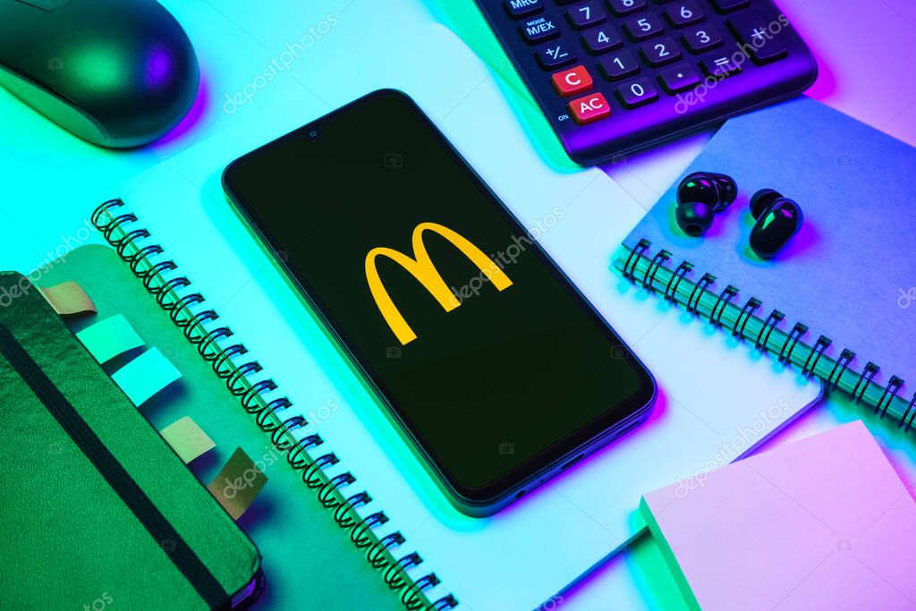 Prague, Czechia - 08 18 2025: An arrangement of office supplies with a mobile phone in the center displaying McDonalds logo. McDonalds is a fast-food chain serving burgers, fries, and more.