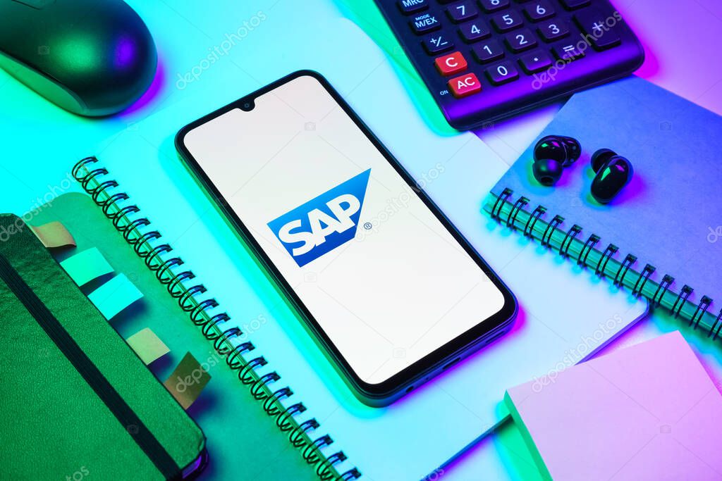 Prague, Czechia - 08 18 2025: An arrangement of office supplies with a mobile phone in the center displaying SAP logo. SAP is a software company providing enterprise applications and solutions.