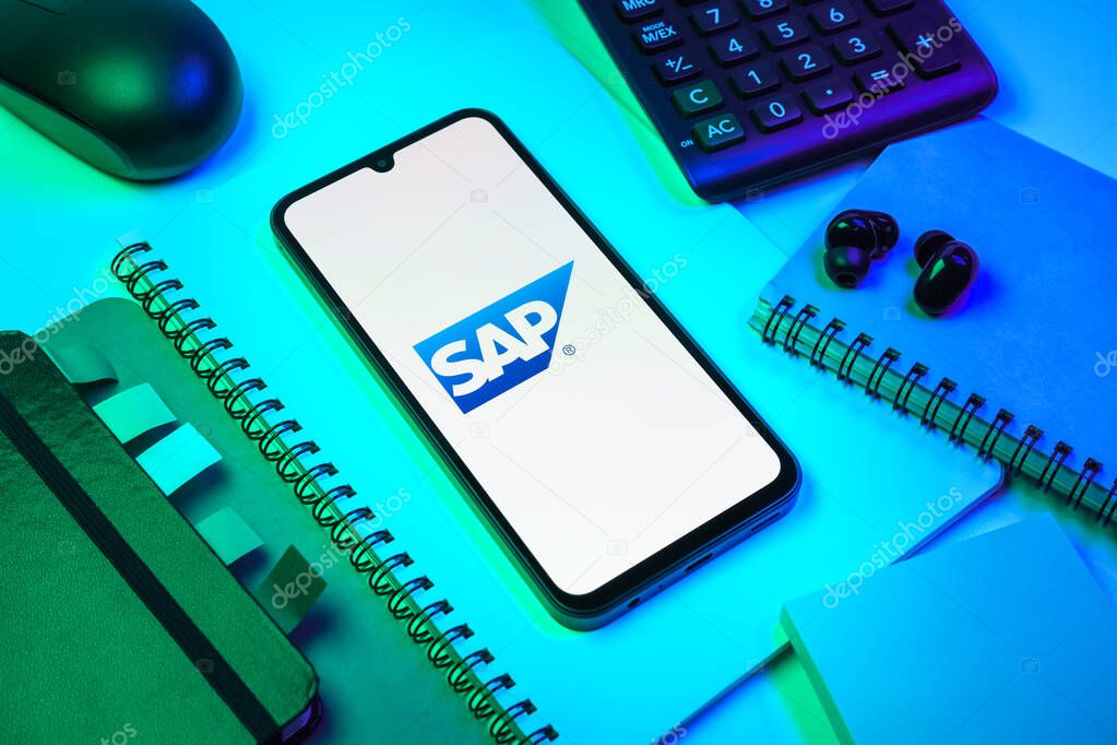 Prague, Czechia - 08 18 2025: An arrangement of office supplies with a mobile phone in the center displaying SAP logo. SAP is a software company providing enterprise applications and solutions.