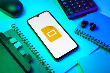 Prag, Çek Cumhuriyeti - 08 18 2025: Merkezde Google Slides logosunu gösteren bir cep telefonu ile ofis malzemeleri düzenlemesi. Google Slides sunumlar ve slayt gösterileri oluşturmak için bir platformdur.