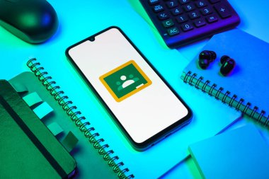 Prag, Çek Cumhuriyeti - 08 18 2025: Merkezde Google Sınıfı logosunu gösteren bir cep telefonu ile ofis malzemeleri düzenlemesi. Google Sınıfı, sınıfları ve eğitim içeriğini yönetmek için bir platformdur.