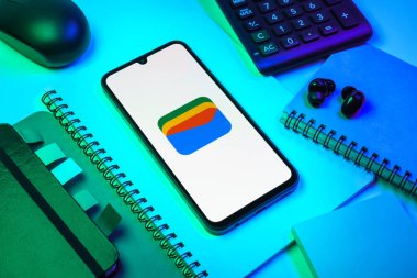 Prag, Çek Cumhuriyeti - 08 18 2025: Merkezde Google Cüzdan logosunu gösteren bir cep telefonu ile ofis malzemeleri düzenlemesi. Google Cüzdanı dijital ödeme yöntemlerini depolamak ve kullanmak için bir platformdur.