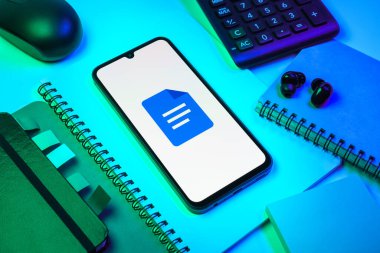 Prag, Çek Cumhuriyeti - 08 18 2025: Merkezde Google Docs logosunu gösteren bir cep telefonu ile ofis malzemeleri düzenlemesi. Google Docs metin belgeleri oluşturmak ve düzenlemek için bir platformdur.