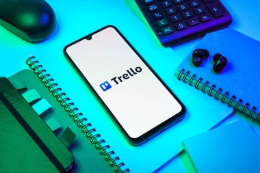 Prag, Çek Cumhuriyeti - 08 18 2025: Merkezde Trello logosu sergilenen bir cep telefonu ile ofis malzemeleri düzenlemesi. Trello, tahta ve görevleri kullanarak proje yönetimi için bir platformdur.