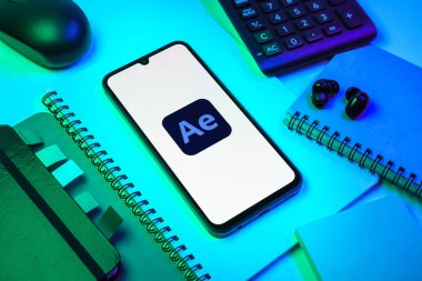 Prag, Çek Cumhuriyeti - 08 18 2025: Ofis malzemelerinin merkezde After Effects logosu sergilenen bir cep telefonu ile düzenlenmesi. After Effects hareket grafikleri ve görsel efektler için bir yazılımdır..