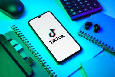 Prag, Çek Cumhuriyeti - 08 18 2025: Merkezde TikTok logosunu gösteren bir cep telefonu ile ofis malzemeleri düzenlemesi. TikTok kısa, yaratıcı ve viral video platformu.