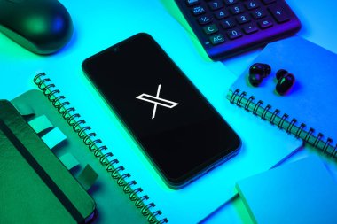 Prag, Çek Cumhuriyeti - 08 18 2025: Merkezinde X logosu sergilenen bir cep telefonu ile ofis malzemeleri düzenlemesi. X, kısa gönderileri ve güncellemeleri paylaşmak için bir platformdur.