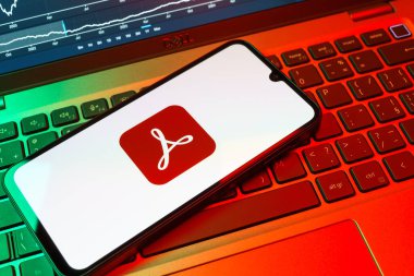 Prag, Çek Cumhuriyeti - 08 18 2025: Klavyede bir cep telefonu Acrobat Reader logosu sergiler. Acrobat Reader, PDF belgelerini görüntülemek ve yönetmek için bir platformdur.