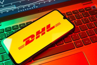 Prag, Çek Cumhuriyeti - 08 18 2025: Klavyede bir cep telefonu DHL logosu sergiler. DHL uluslararası nakliye hizmeti sunan bir lojistik şirketidir..