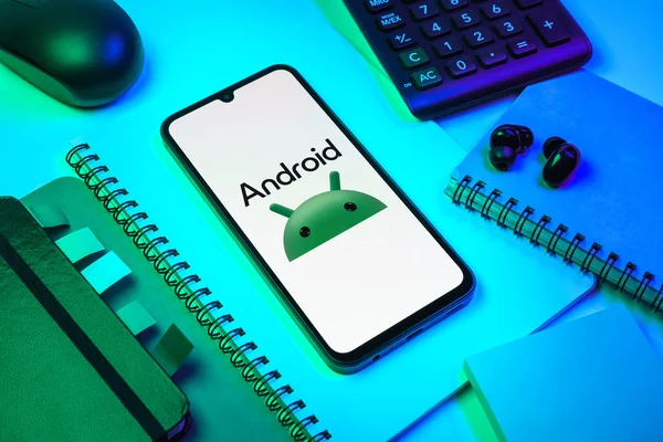 Prag, Çek Cumhuriyeti - 08 18 2025: Merkezde Android logosunu gösteren bir cep telefonu ile ofis malzemeleri düzenlemesi. Android akıllı telefonlar ve tabletler için mobil bir işletim sistemidir..