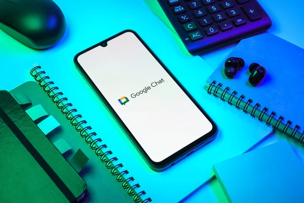 Prag, Çek Cumhuriyeti - 08 18 2025: Merkezde Google Chat logosunu gösteren bir cep telefonu ile ofis malzemeleri düzenlemesi. Google Chat mesajlaşma ve takım işbirliği için bir platformdur.
