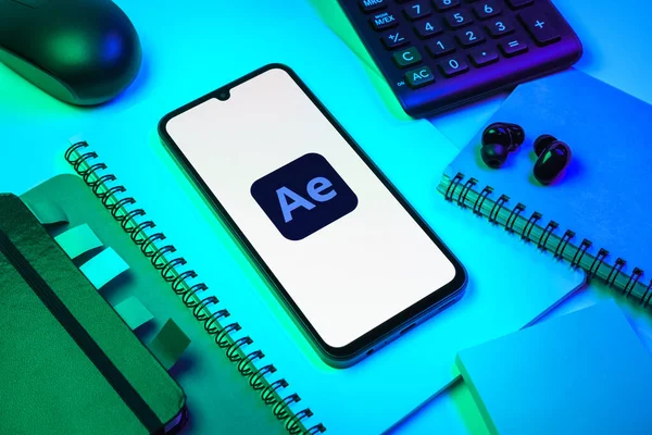 Prag, Çek Cumhuriyeti - 08 18 2025: Ofis malzemelerinin merkezde After Effects logosu sergilenen bir cep telefonu ile düzenlenmesi. After Effects hareket grafikleri ve görsel efektler için bir yazılımdır..
