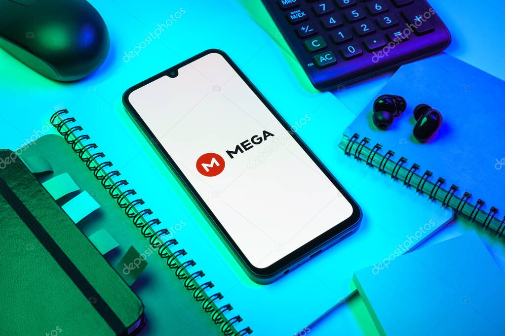 Prague, Czechia - 08 18 2025: An arrangement of office supplies with a mobile phone in the center displaying Mega logo. Mega is a platform for cloud storage with encrypted file sharing.