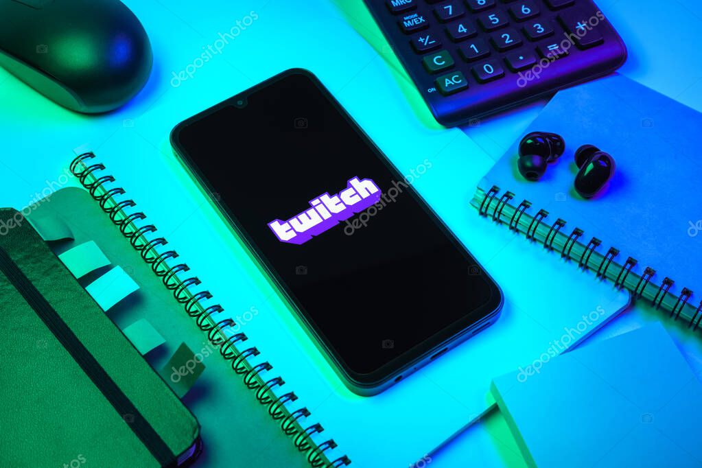 Prague, Czechia - 08 18 2025: An arrangement of office supplies with a mobile phone in the center displaying Twitch logo. Twitch is a platform for live streaming games and content.