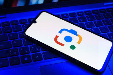 Prag, Çek Cumhuriyeti - 09 02 2025: Laptop klavyesindeki telefon renkli ışıkla aydınlatılmış Google Lens logosunu gösteriyor. Google Lens, resimlerdeki görsel arama ve bilgi için kullanılan bir araçtır..