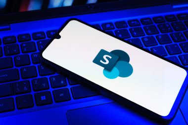 Prag, Çek Cumhuriyeti - 09 02 2025: Microsoft Sharepoint logosunun renkli ışıklarla aydınlatıldığı dizüstü bilgisayardaki telefon. Microsoft Sharepoint işbirliği ve belge yönetimi için bir platformdur.