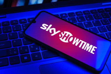 Prag, Çek Cumhuriyeti - 09 02 2025: Renkli ışık tarafından aydınlatılan dizüstü bilgisayardaki telefon SkyShowtime logosunu gösteriyor. SkyShowtime, sinema ve televizyon dizileri için bir yayın platformudur..