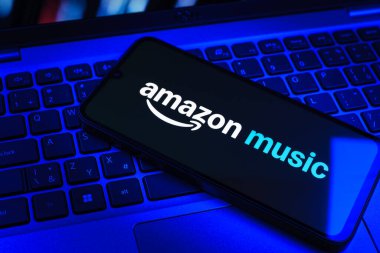 Prag, Çek Cumhuriyeti - 09 02 2025: Renkli ışık tarafından aydınlatılan dizüstü bilgisayardaki telefon Amazon Müzik logosunu gösteriyor. Amazon Müzik müzik müzik için bir platformdur..