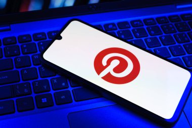 Prag, Çek Cumhuriyeti - 09 02 2025: Pinterest logosunun renkli ışıklarla aydınlatıldığı dizüstü bilgisayardaki telefon. Pinterest fikirleri görsel olarak keşfetmek ve kaydetmek için bir platformdur..
