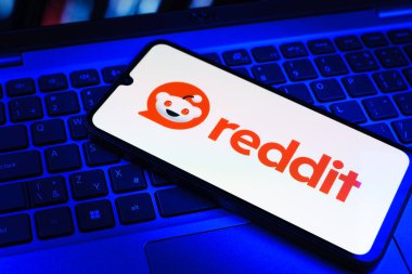 Prag, Çek Cumhuriyeti - 09 02 2025: Renkli ışık tarafından yakılan dizüstü bilgisayardaki telefon Reddit logosunu gösteriyor. Reddit tartışma, haber ve toplum içeriği için bir platformdur.