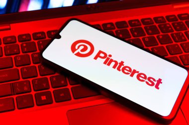 Prag, Çek Cumhuriyeti - 09 02 2025: Pinterest logosunun renkli ışıklarla aydınlatıldığı dizüstü bilgisayardaki telefon. Pinterest fikirleri görsel olarak keşfetmek ve kaydetmek için bir platformdur..