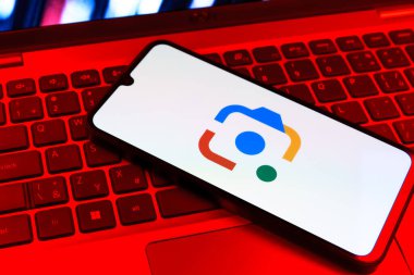 Prag, Çek Cumhuriyeti - 09 02 2025: Laptop klavyesindeki telefon renkli ışıkla aydınlatılmış Google Lens logosunu gösteriyor. Google Lens, resimlerdeki görsel arama ve bilgi için kullanılan bir araçtır..