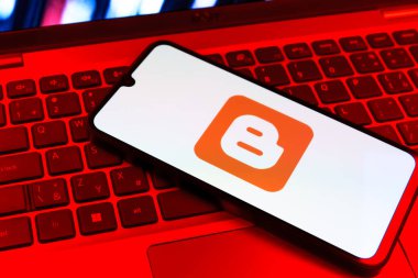 Prag, Çek Cumhuriyeti - 09 02 2025: Renkli ışık tarafından aydınlatılan dizüstü bilgisayardaki telefon blogger logosunu gösteriyor. Blogger blog oluşturma ve yayınlama için bir platformdur.