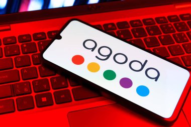 Prag, Çek Cumhuriyeti - 09 02 2025: Telefonun klavyesi renkli ışıklarla aydınlatılmış Agoda logosu gösteriyor. Agoda, otelleri ve seyahat yerlerini ayırtmak için bir platform..