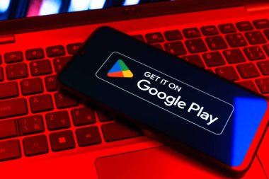 Prag, Çek Cumhuriyeti - 09 02 2025: Google Play logosunun renkli ışıklarla aydınlatıldığı dizüstü bilgisayardaki telefon. Google Play uygulamaları, oyunları ve dijital içeriği indirmek için bir platformdur.