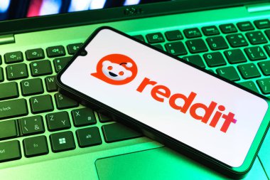Prag, Çek Cumhuriyeti - 09 02 2025: Renkli ışık tarafından yakılan dizüstü bilgisayardaki telefon Reddit logosunu gösteriyor. Reddit tartışma, haber ve toplum içeriği için bir platformdur.