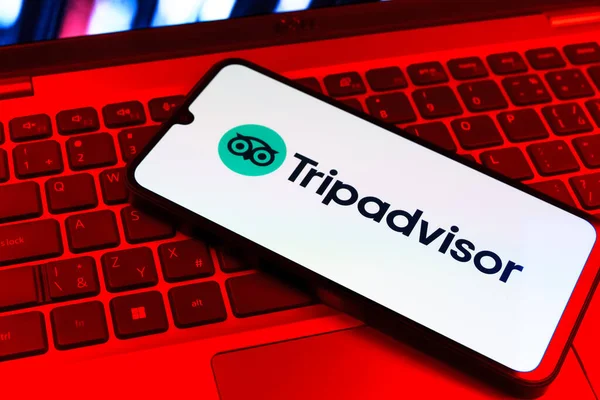 Prag, Çek Cumhuriyeti - 09 02 2025: Renkli ışık tarafından yakılan dizüstü bilgisayardaki telefon TripDanışman logosunu gösteriyor. Seyahat danışmanı seyahat değerlendirmeleri, rezervasyonlar ve tavsiyeler için bir platformdur..