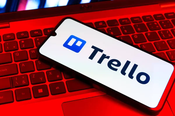 Prag, Çek Cumhuriyeti - 09 02 2025: Renkli ışık tarafından yakılan dizüstü bilgisayardaki telefon Trello logosunu gösteriyor. Trello, tahta ve görevleri kullanarak proje yönetimi için bir platformdur.