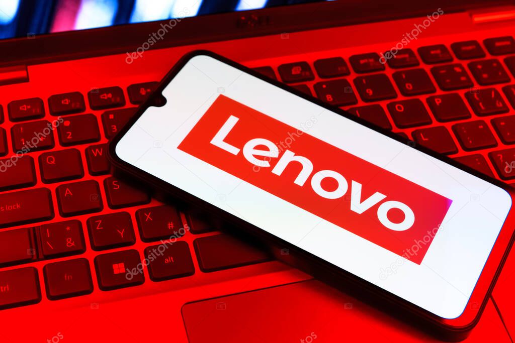 Prague, Czechia - 09 02 2025: Phone on laptop keyboard lit by colored light shows Lenovo logo. Lenovo is a technology company producing computers and electronics.