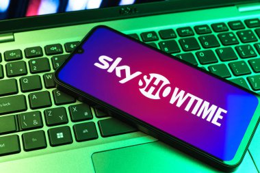 Prag, Çek Cumhuriyeti - 09 02 2025: Renkli ışık tarafından aydınlatılan dizüstü bilgisayardaki telefon SkyShowtime logosunu gösteriyor. SkyShowtime, sinema ve televizyon dizileri için bir yayın platformudur..
