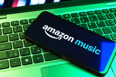 Prag, Çek Cumhuriyeti - 09 02 2025: Renkli ışık tarafından aydınlatılan dizüstü bilgisayardaki telefon Amazon Müzik logosunu gösteriyor. Amazon Müzik müzik müzik için bir platformdur..