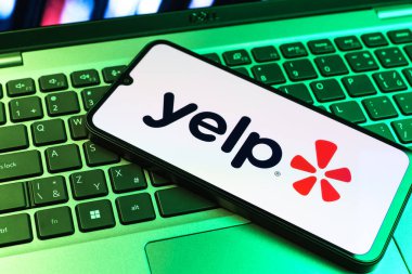 Prag, Çek Cumhuriyeti - 09 02 2025: Renkli ışık tarafından yakılan dizüstü bilgisayardaki telefon Yelp logosunu gösteriyor. Yelp yerel işletmeleri bulmak ve incelemek için bir platformdur.