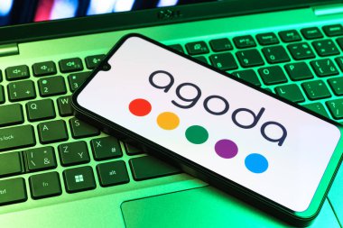 Prag, Çek Cumhuriyeti - 09 02 2025: Telefonun klavyesi renkli ışıklarla aydınlatılmış Agoda logosu gösteriyor. Agoda, otelleri ve seyahat yerlerini ayırtmak için bir platform..