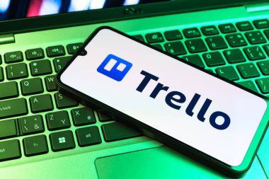 Prag, Çek Cumhuriyeti - 09 02 2025: Renkli ışık tarafından yakılan dizüstü bilgisayardaki telefon Trello logosunu gösteriyor. Trello, tahta ve görevleri kullanarak proje yönetimi için bir platformdur.