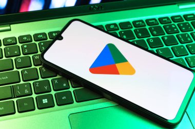 Prag, Çek Cumhuriyeti - 09 02 2025: Google Play logosunun renkli ışıklarla aydınlatıldığı dizüstü bilgisayardaki telefon. Google Play uygulamaları, oyunları ve dijital içeriği indirmek için bir platformdur.