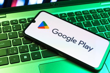 Prag, Çek Cumhuriyeti - 09 02 2025: Google Play logosunun renkli ışıklarla aydınlatıldığı dizüstü bilgisayardaki telefon. Google Play uygulamaları, oyunları ve dijital içeriği indirmek için bir platformdur.