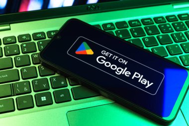 Prag, Çek Cumhuriyeti - 09 02 2025: Google Play logosunun renkli ışıklarla aydınlatıldığı dizüstü bilgisayardaki telefon. Google Play uygulamaları, oyunları ve dijital içeriği indirmek için bir platformdur.