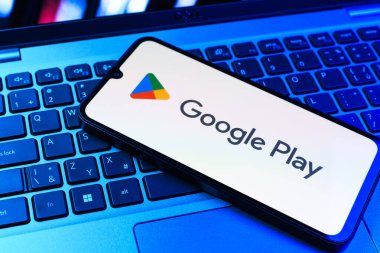 Prag, Çek Cumhuriyeti - 09 02 2025: Google Play logosunun renkli ışıklarla aydınlatıldığı dizüstü bilgisayardaki telefon. Google Play uygulamaları, oyunları ve dijital içeriği indirmek için bir platformdur.