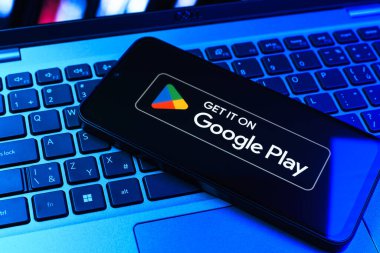 Prag, Çek Cumhuriyeti - 09 02 2025: Google Play logosunun renkli ışıklarla aydınlatıldığı dizüstü bilgisayardaki telefon. Google Play uygulamaları, oyunları ve dijital içeriği indirmek için bir platformdur.