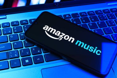 Prag, Çek Cumhuriyeti - 09 02 2025: Renkli ışık tarafından aydınlatılan dizüstü bilgisayardaki telefon Amazon Müzik logosunu gösteriyor. Amazon Müzik müzik müzik için bir platformdur..