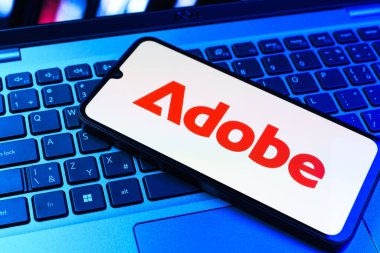 Prag, Çek Cumhuriyeti - 09 02 2025: Telefonun klavyesinde renkli ışık gösterileri Adobe logosu var. Adobe yaratıcı araçlar ve hizmetler sunan bir yazılım şirketidir..