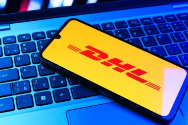 Prag, Çek Cumhuriyeti - 09 02 2025: DHL logosu renkli ışık tarafından yakılan dizüstü bilgisayardaki telefon. DHL uluslararası nakliye hizmeti sunan bir lojistik şirketidir..