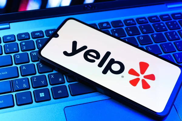 Prag, Çek Cumhuriyeti - 09 02 2025: Renkli ışık tarafından yakılan dizüstü bilgisayardaki telefon Yelp logosunu gösteriyor. Yelp yerel işletmeleri bulmak ve incelemek için bir platformdur.